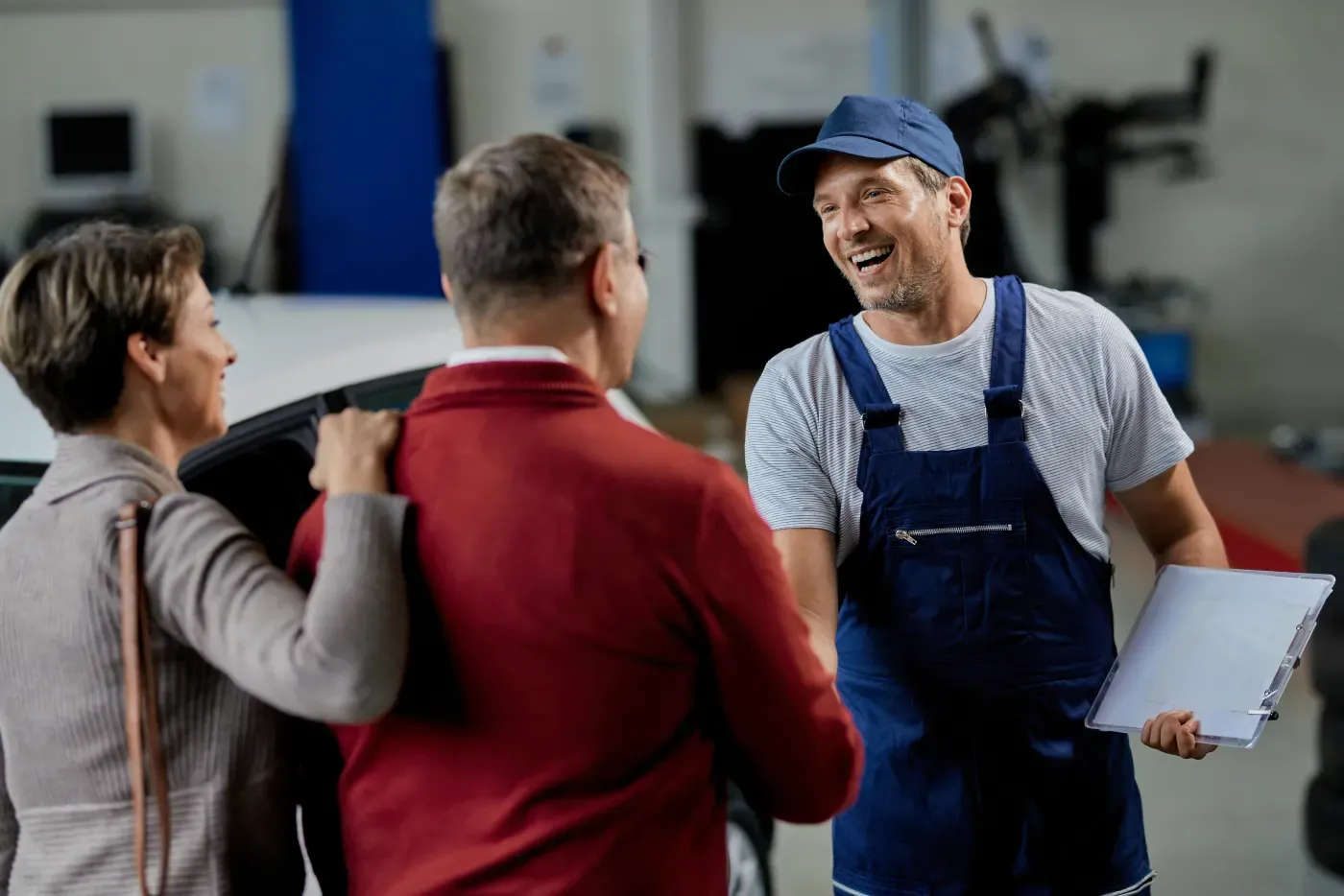 Satisfied customers shaking hands with a happy auto shop owner
